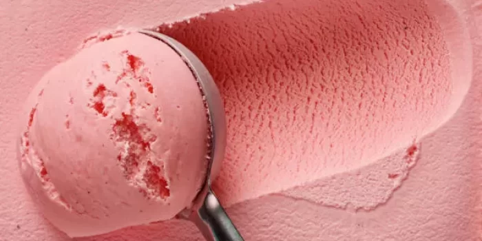 pink strawberry ice cream ball in a spoon, top view